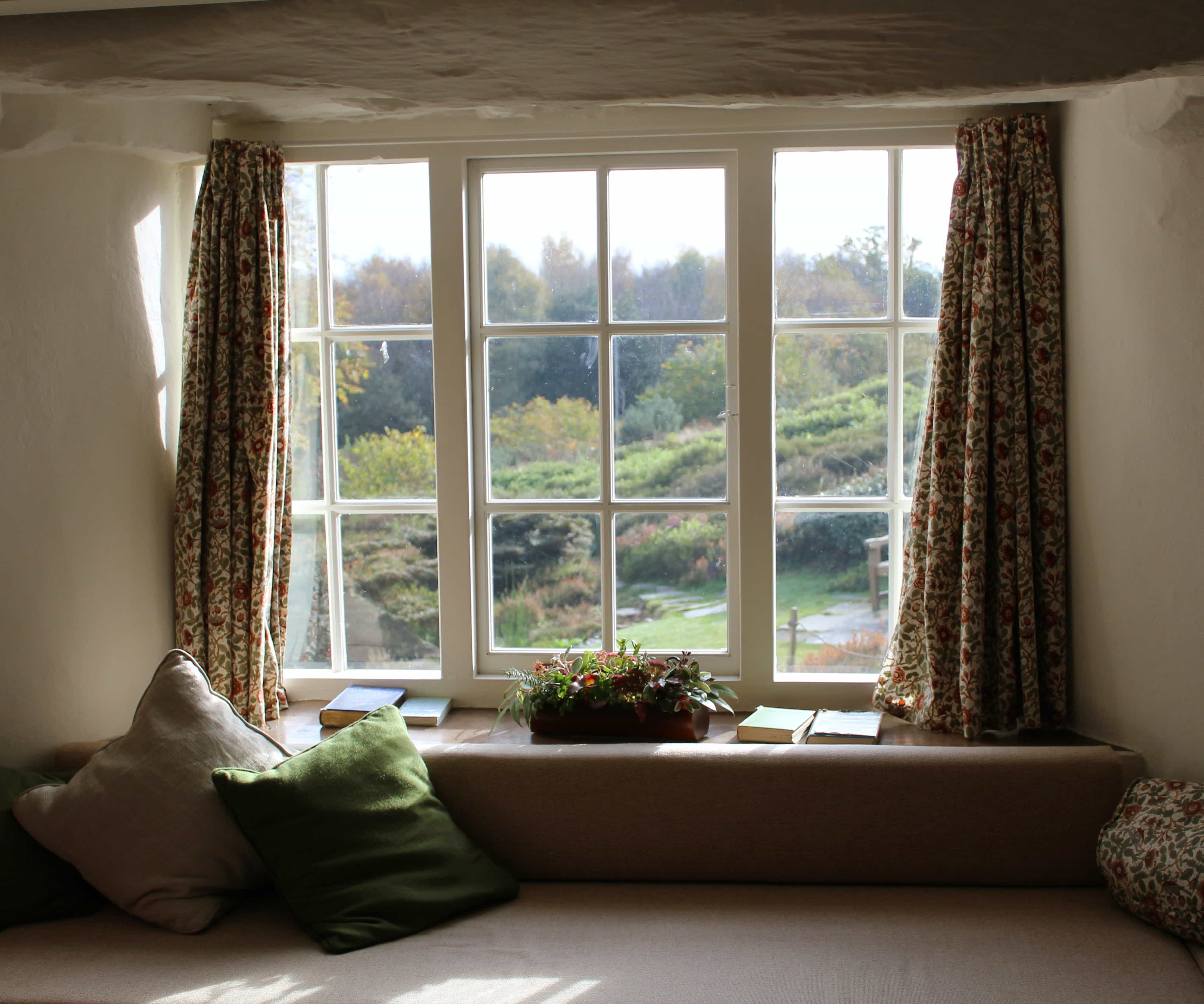 A cozy day bed with curtains on the window.